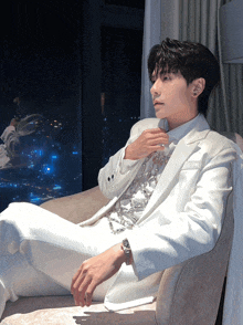 a man in a white suit is sitting on a couch