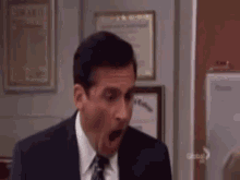 a man in a suit and tie is making a surprised face in a room .