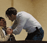 a man in a white shirt is holding another man 's hands
