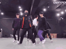 a group of young men are dancing in a dark room with the words enhypen written on the ceiling