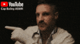 a man points to a chair in the corner with a youtube logo above him