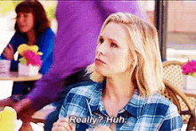 a woman in a plaid shirt is sitting at a table talking to another woman .