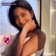 a woman is smiling with her hand on her chin and a pink butterfly is behind her .