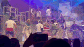 a person taking a picture of a group of people dancing on a stage
