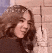 a woman is standing in front of a brick wall holding a rope .