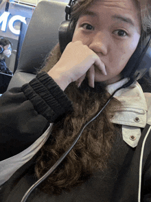 a woman wearing headphones is sitting in front of a sign that says 1c