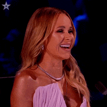 a woman in a white dress is laughing with an american star in the corner