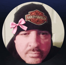 a man wearing a black harley davidson beanie with a pink bow