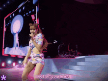 a woman dancing on a stage with out of your mind written on the bottom right
