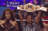 a referee is holding a wrestling championship belt in front of a crowd of people .