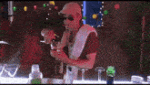 a man in a white hat and sunglasses is pouring a drink into a glass