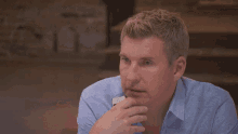 a man in a blue shirt is holding his head