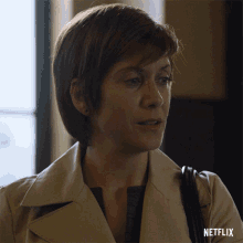 a woman in a trench coat with a netflix logo on the bottom right