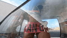 a woman in a red skirt with the word tan on it is standing in a car