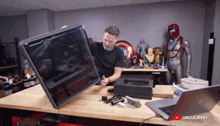 a man is holding a large screen in front of a laptop that says unclejessy on the bottom right