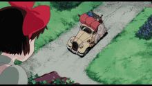 a girl with a red bow on her head looks at a yellow car with luggage on the back