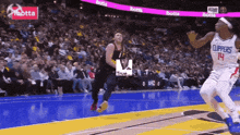 a basketball player with the number 14 on his jersey jumps in the air