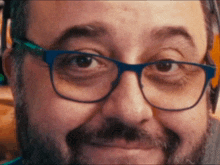 a man with glasses and a beard is smiling and looking at the camera