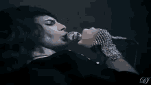 a man is singing into a microphone while wearing a bracelet .