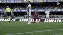 a soccer player kneeling on the field in front of a banner that says nostra unica fede