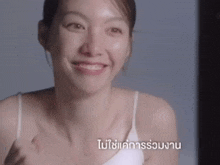 a woman in a white tank top is smiling in a video in a language that is not english