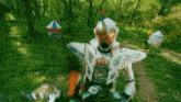 a person in a white and orange costume stands in a forest