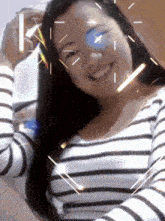 a woman in a striped shirt is smiling with sparks around her