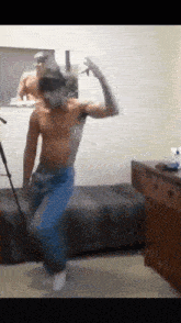 a shirtless man is dancing in front of a mirror .