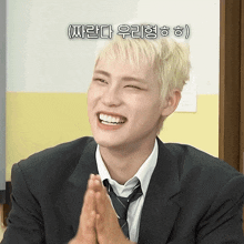 a young man in a suit and tie is smiling with a foreign language behind him