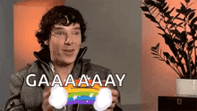 a man is holding a rainbow colored object in his hands and says gaaaa ay .