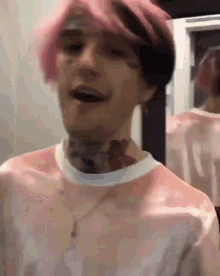 a man with pink hair is smiling in front of a mirror