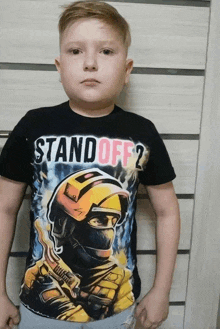 a boy wearing a black t-shirt that says " standoff 2 "