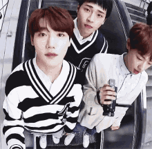 three young men are standing on an escalator looking at the camera .