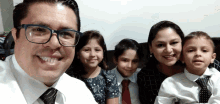 a man with glasses and a tie poses with his family