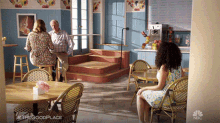 a woman is sitting at a table in a restaurant talking to a man and another woman .