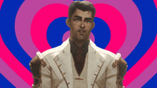 a man in a suit is standing in front of a pink and blue heart shaped background