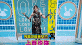 a woman stands in front of a sign that says love love love
