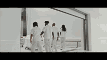 a group of people in white uniforms are walking down a hospital hallway