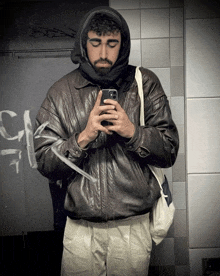 a man in a leather jacket takes a picture of himself in a mirror