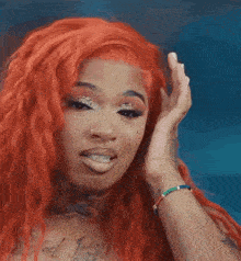 a woman with red hair is smiling and covering her ear with her hand