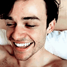 a man without a shirt is smiling and looking at the camera