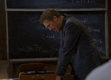 a man in a suit stands in front of a blackboard that says in the normal count of blood