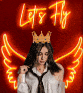 a woman with a crown on her head stands in front of a let 's fly neon sign