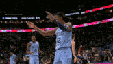 a basketball player wearing a grizzlies jersey points to the crowd