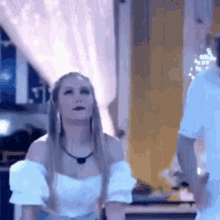 a woman in a white off the shoulder top is standing next to a man in a white shirt