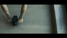 a man is rolling an exercise wheel on a wooden floor with the name lupsgarvel27 below him
