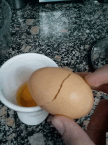a cracked egg sits on a counter next to a white cup