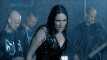 a woman in a black dress is standing in the rain with a group of men behind her