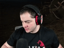 a man wearing headphones is sitting in front of a microphone and making a funny face .