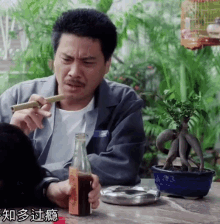 a man sitting at a table smoking a cigar and drinking a bottle